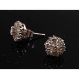 A pair of white metal diamond circular cluster ear studs, each featuring seven round brilliant cut