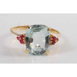 A yellow metal, aquamarine and ruby dress ring, comprising a cushion shaped aquamarine in a four-