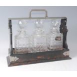 A late Victorian coromandel and silver plated tantalus, having three hobnail cut square glass