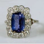 A white metal, tanzanite and diamond oblong cluster ring, featuring a centre oval tanzanite in a