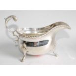A silver sauceboat in the George III style, having a gadrooned rim, flying S-scroll handle, and