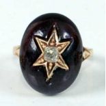 A yellow metal oval garnet mourning ring, featuring an oval cabochon cut garnet with centre six-