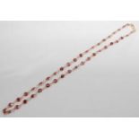 A yellow metal and garnet set multi-stone necklet, featuring forty-one round faceted garnets in