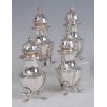 An Edwardian set of four silver pepperettes, each having finial topped pierced dome covers, raised