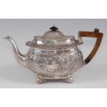 A late Victorian silver teapot, of oval bombe form, embossed with C-scrolls, leaves and flowers, the