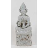 A Chinese celadon glazed stoneware deity, in Vitarka Mudra pose and seated upon a lotus flowers base