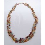 A yellow metal multi-stone fringe necklet, comprising oval faceted garnets, blue topaz, amethyst,