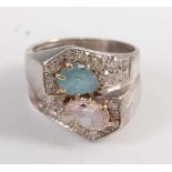 A white metal crossover ring, comprising a pear shaped aquamarine, a pear shaped pink sapphire,