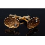 A pair of yellow metal cufflinks, each comprising an oval concave bark finished plate with an offset