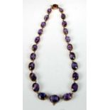 A yellow metal amethyst necklet, featuring 24 graduated oval amethysts including one in integral