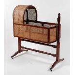 An early Victorian mahogany crib, having split cane sides and domed head, the whole raised on ring