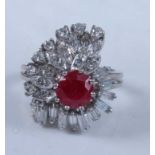 A white metal, ruby and diamond cocktail ring, featuring a centre round faceted ruby within a border