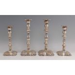 A set of four Edwardian silver table candlesticks, each having leaf embossed flaring sconces and