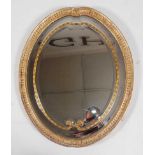 *A George III gilt gesso wall mirror, having a central bevelled oval plate with further outer double