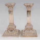 A pair of Edwardian silver candlesticks, each having detachable sconces over embossed collars, and