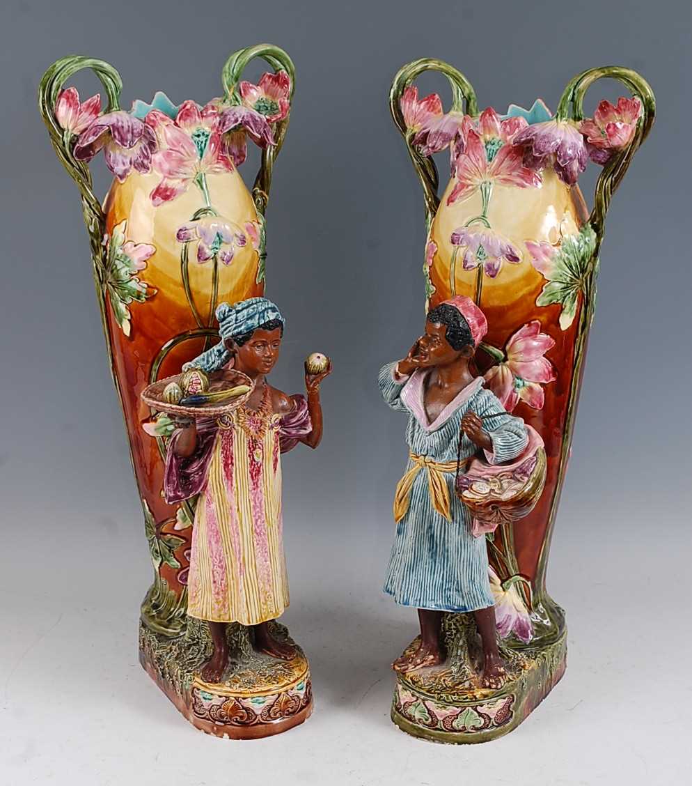 A pair of large Art Nouveau majolica glazed pottery twin handled figural vases, with profusely