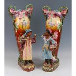 A pair of large Art Nouveau majolica glazed pottery twin handled figural vases, with profusely