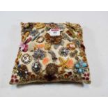 A crocheted silk cushion, set with a collection of paste set brooches