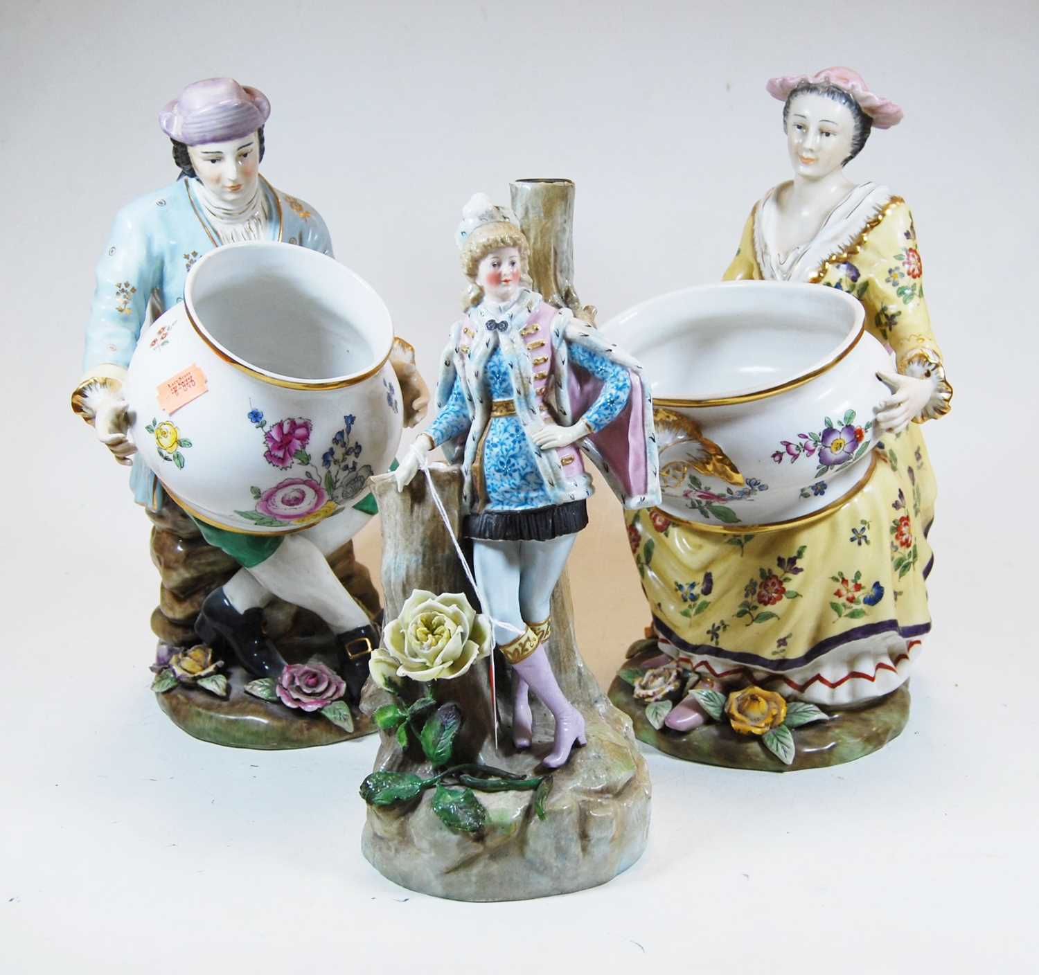 A pair of 20th century pottery figures of a seated couple, each holding an oversized bowl, crossed