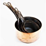 A graduated set of four copper saucepans, each having wrought iron handles, the largest dia.24cm