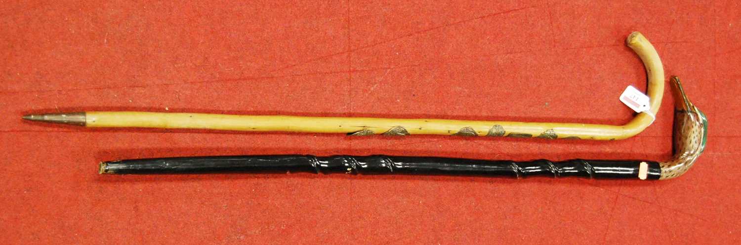 A contemporary walking cane, having a black painted shaft, the handle carved and painted as a