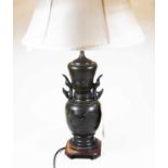 A Japanese bronzed metal twin handled table lamp of baluster form with raised floral decoration