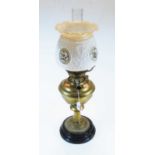 An early 20th century brass pedestal oil lamp, having opalescent glass shade above a brass font,