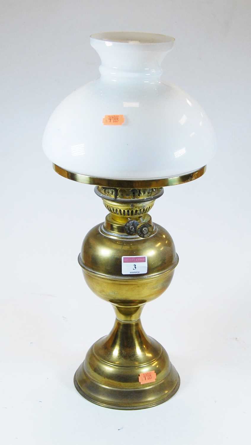 An early 20th century glass oil lamp, the milk glass shade above a circular reservoir and foot, h.