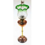 An early 20th century brass and copper pedestal oil lamp, having frilled green tinted etched glass