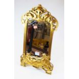 An Art Nouveau style gilt framed easel mirror, decorated with stylised foliage and a reclining