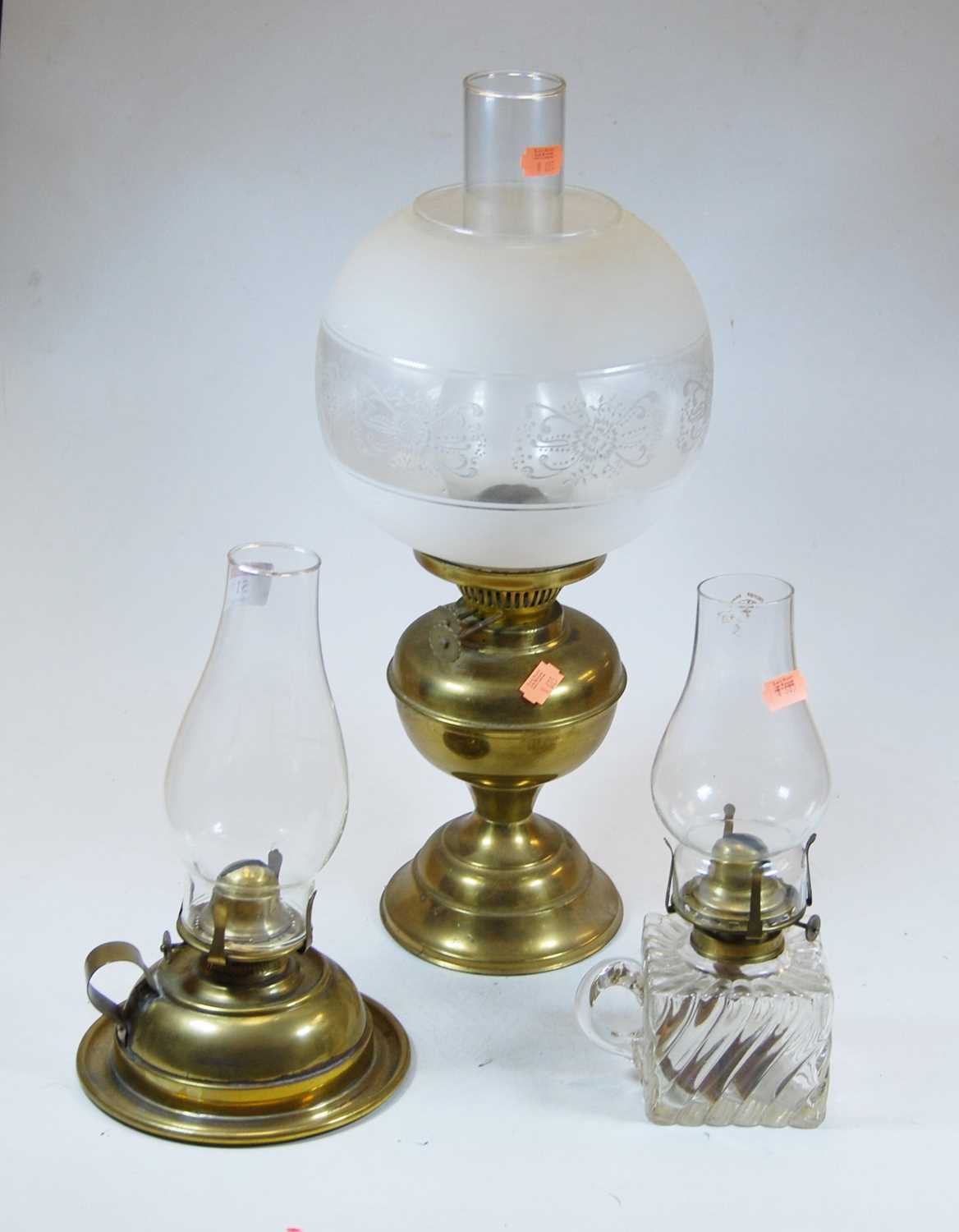 An early 20th century brass oil lamp, with later shade, h.46cm; together with two others (3)