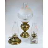 An early 20th century brass oil lamp, with later shade, h.46cm; together with two others (3)