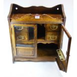 An Edwardian oak smokers cabinet, having central recess flanked by four short drawers, enclosed by a