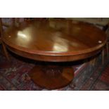 An early Victorian rosewood circular tilt-top pedestal breakfast table, raised on octagonal