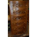 A contemporary stained pine narrow serpentine front chest of six long drawers, on squat bun