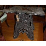 An early 20th century Indian stained and relief carved teak low occasional table, having floral
