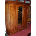 A Victorian mahogany triple wardrobe, having arched mirrored central door flanked by conforming