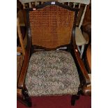 An early 20th century oak cane back and floral tapestry seat open armchair, w.56cm