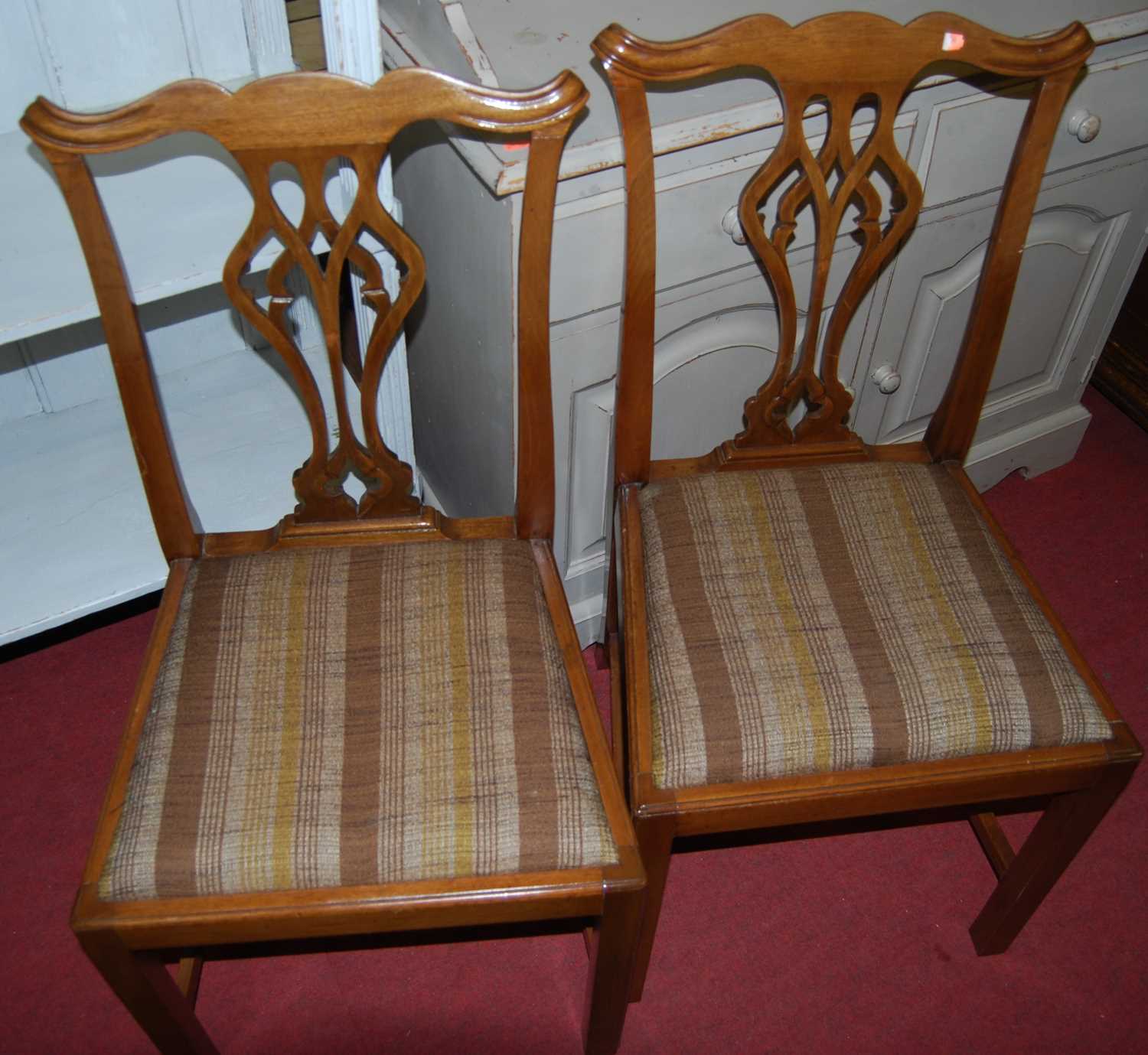 A set of four mahogany Chippendale style dining chairs, each having striped fabric upholstered