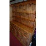 A modern pine long kitchen dresser, having two-tier open plate rack, over base fitted with four