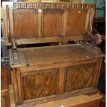 An early 20th century oak and beech twin panelled monks bench, having a fold over top with hinged