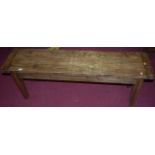 A stained pine bench, having cleated ends on tapering square supports, length 133cm