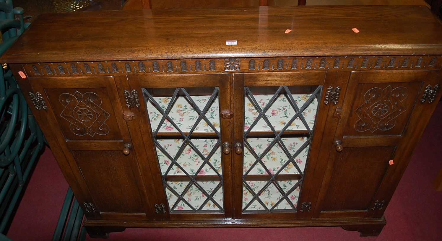 A contemporary moulded and joined oak side cabinet, having twin lead glazed central doors, flanked