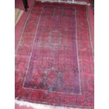A Persian red ground woollen rug (worn), 240 x 134cm