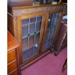 A 1920s oak double door lead glazed bookcase, raised on squat bulbous supports to lower
