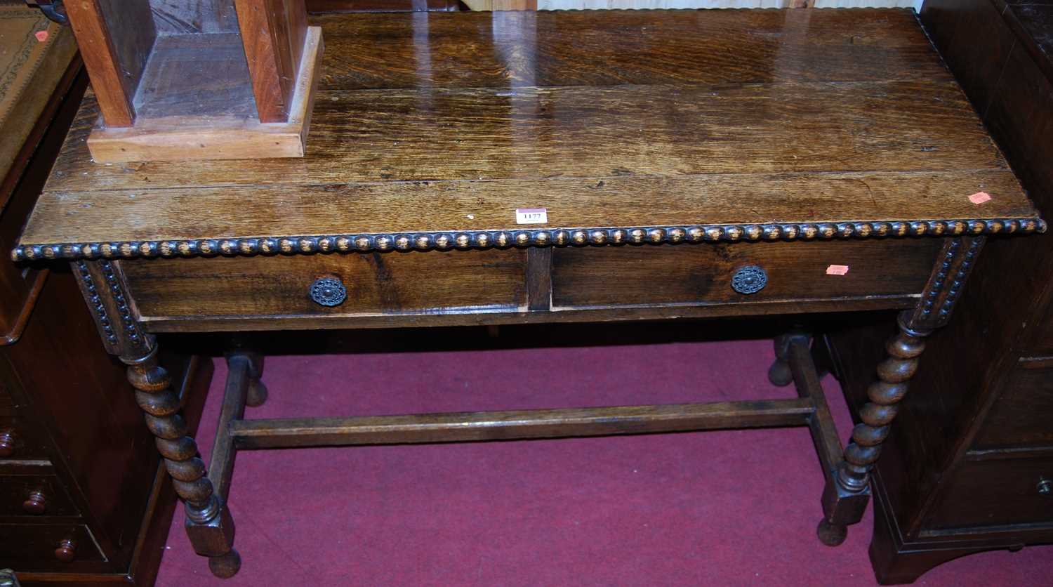 A 1920s oak barleytwist two-tier side table, having a beaded edge, w.108cm