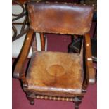 An early 20th century Cromwellian style bobbin turned oak tan leather and studded open armchair,