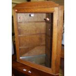 An early 20th century oak single door glazed hanging corner cupboard