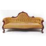 A Victorian mahogany framed settee, of serpentine outline, having a swept back, the whole re-