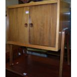 A 1960s walnut low double door side cupboard, having interior magazine compartments, width 65cm